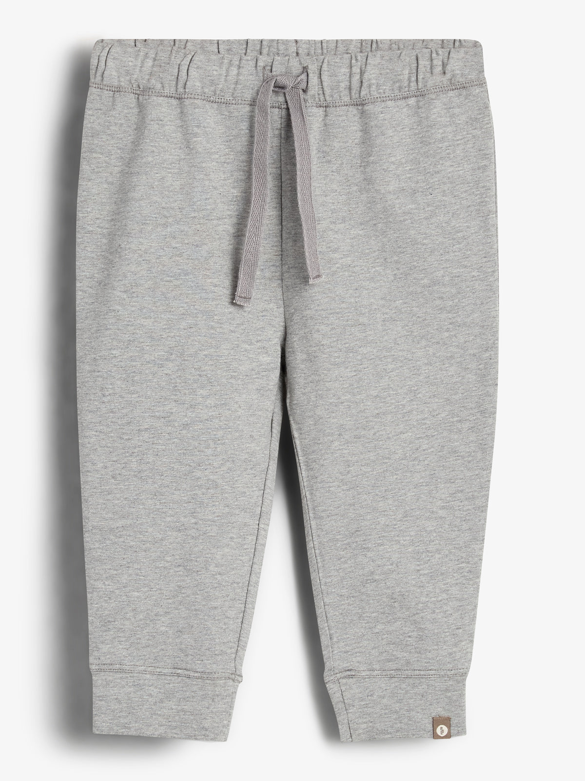 Graue Jogginghose mit Kordelzug in der Taille, entspannt hängend. Der Stoff wirkt weich und bequem. Die Umgebung ist ein neutraler, weißer Hintergrund ohne zusätzliche Details.