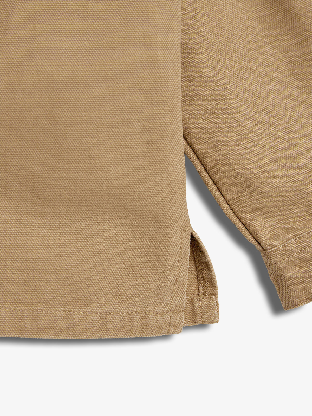 A close-up of a beige fabric garment showing a hem and slit detail, highlighting the texture and stitching. The background is plain white.