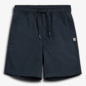 Dark blue shorts are laid flat, featuring an elastic waistband with a drawstring. A small logo patch is visible on the side. They are set against a plain white background.