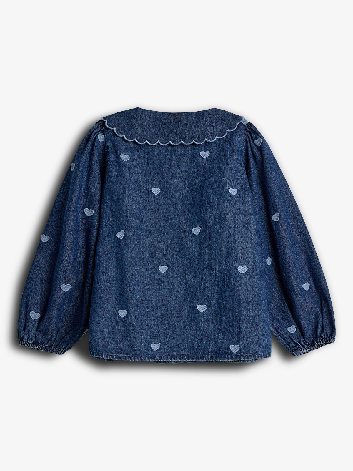 A denim blouse with long sleeves and scalloped collar features light blue embroidered hearts, set against a plain light background.