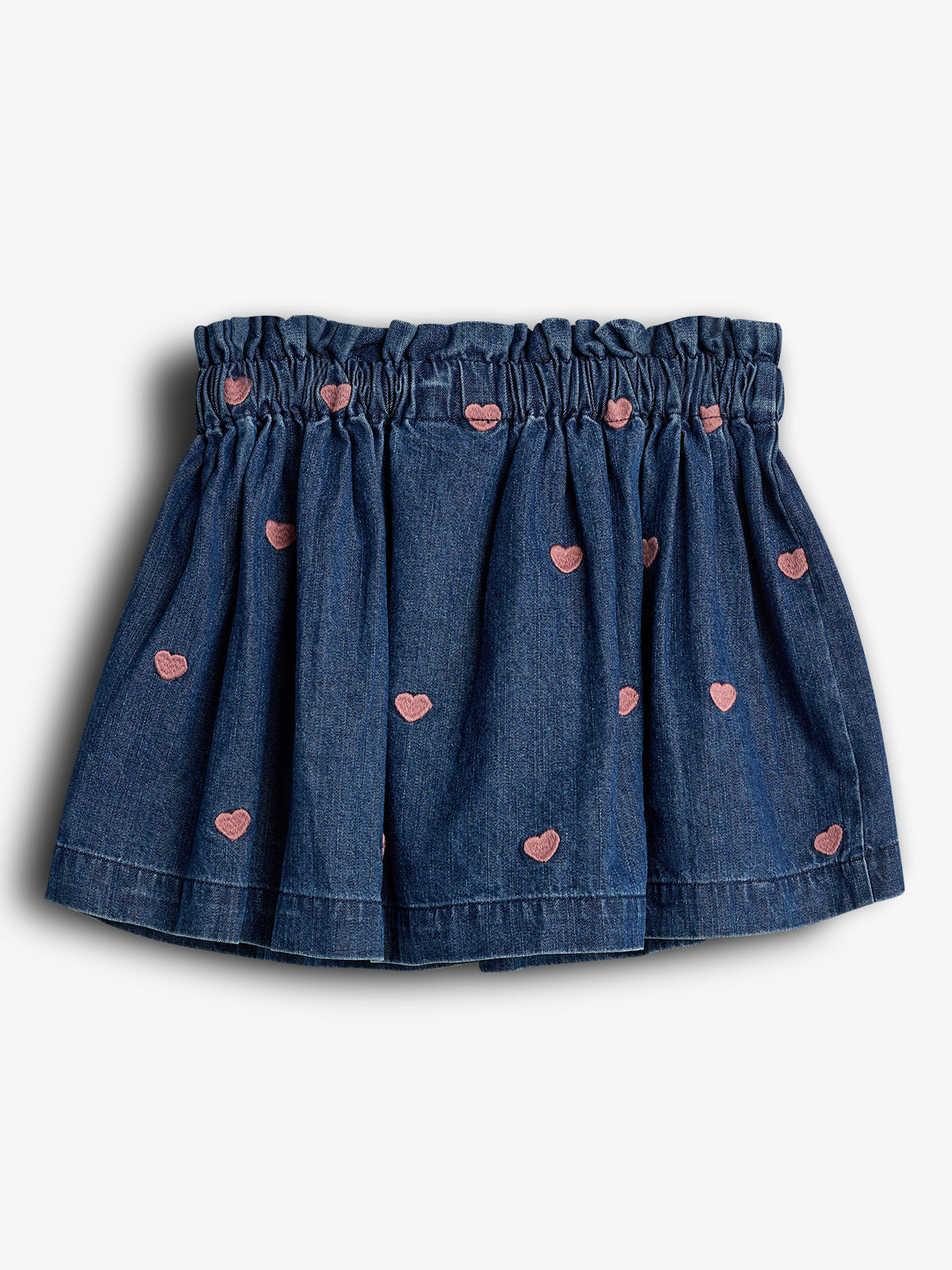 A blue denim skirt, featuring an elastic waistband and pink heart embroidery, hangs against a plain white background.
