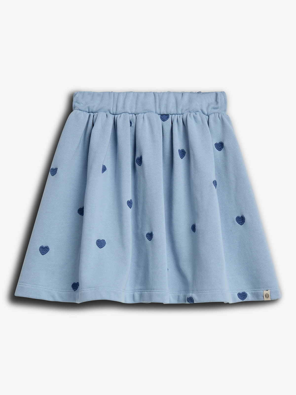 A light blue skirt features small, dark blue heart patterns, gathered at the waistband, shown against a plain white background.