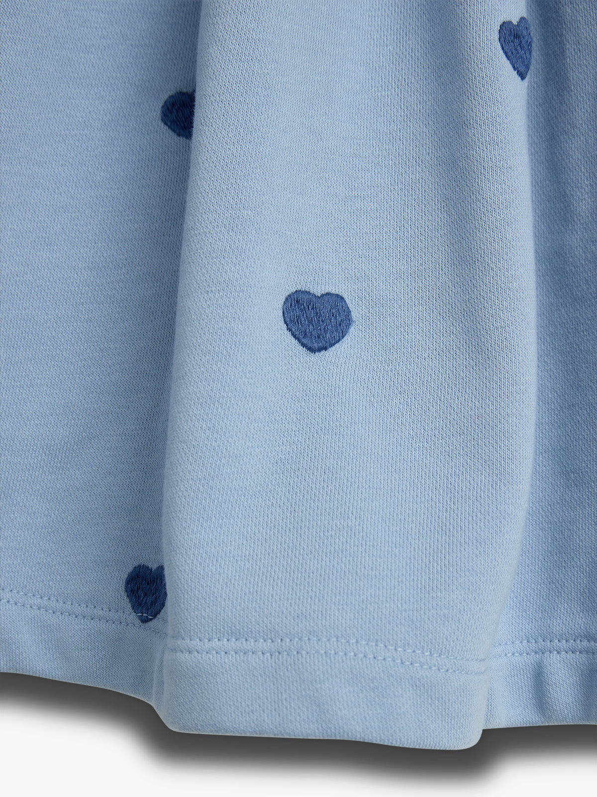 Light blue fabric with dark blue heart patterns scattered throughout it, draping vertically. The fabric's texture is soft and slightly textured, suggesting gentle folds.