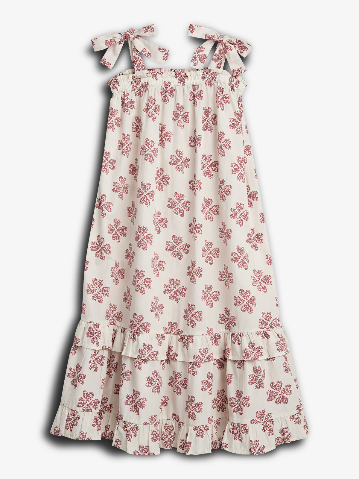 A white dress with red floral patterns hangs still, featuring adjustable shoulder tie straps and a tiered ruffled hem, set against a plain white background.