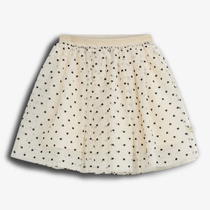 A cream-colored skirt features a pattern of small black hearts. It is pleated with a gold elastic waistband, displayed against a plain white background.
