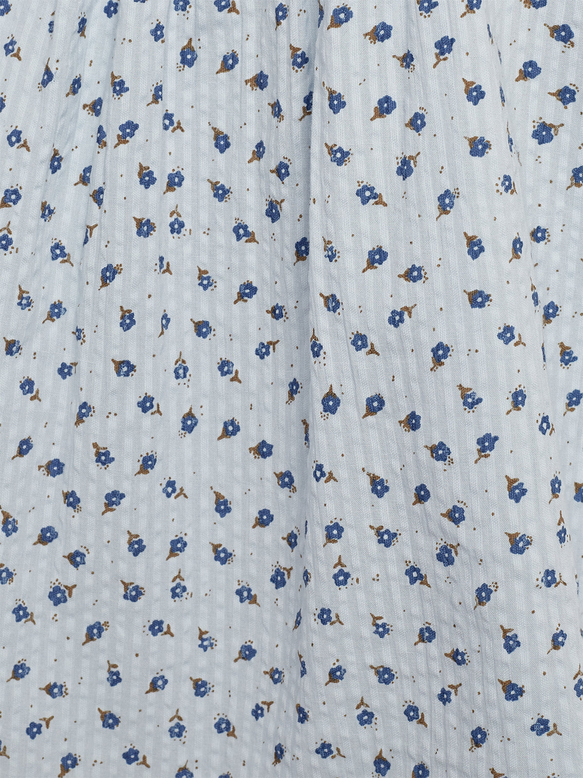 Blue and brown floral patterns are scattered across light fabric, creating a textured appearance. The material features small, repeated flower motifs, giving it a delicate, vintage look.