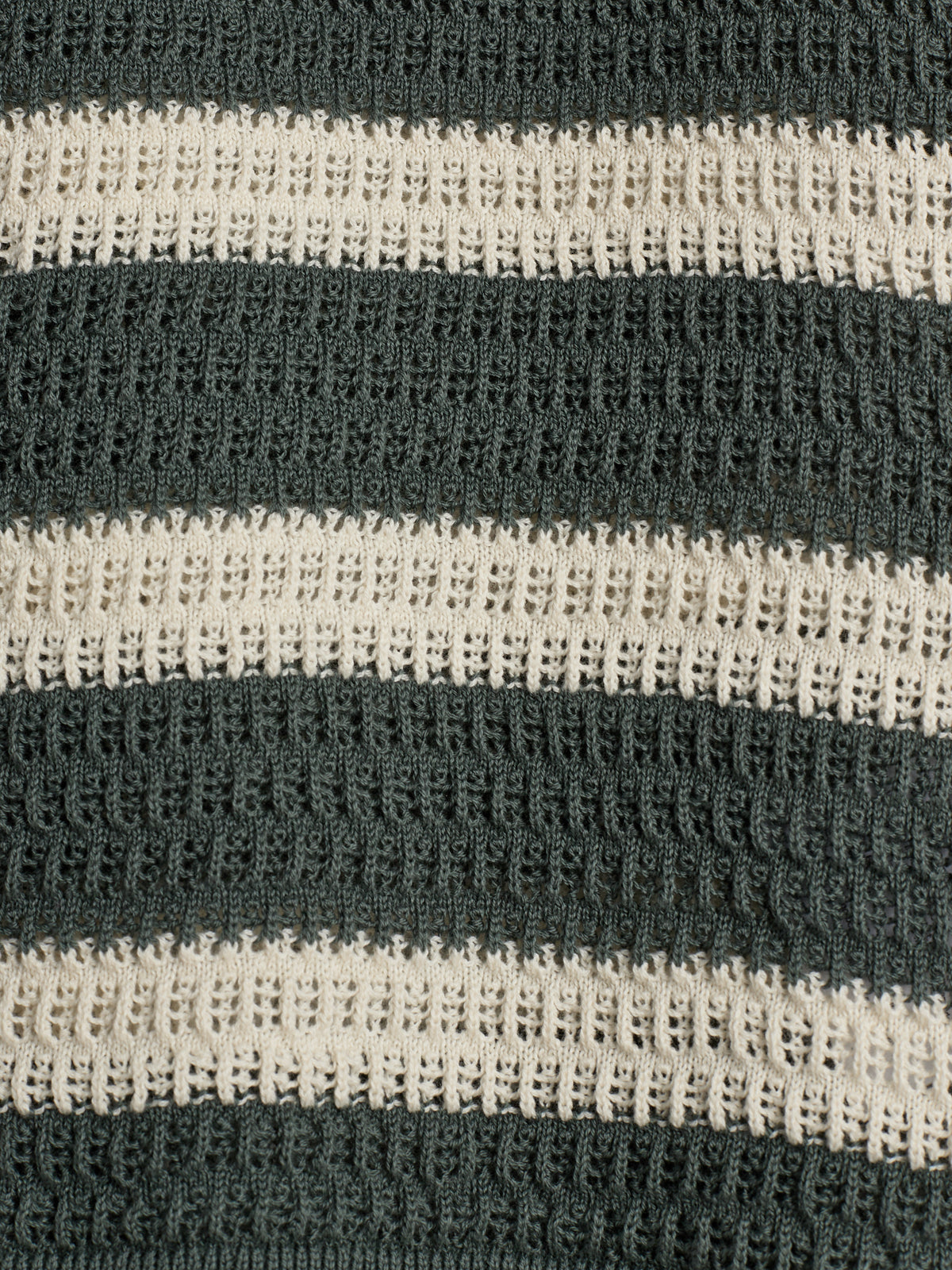 Striped knitted fabric shows alternating bands of dark green and cream colors with a detailed, textured pattern.