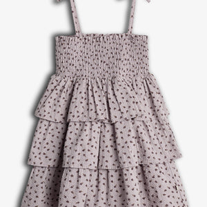 A sleeveless, lavender dress with thin shoulder straps features tiered ruffles and a small floral pattern, creating a delicate, layered appearance against a plain background.