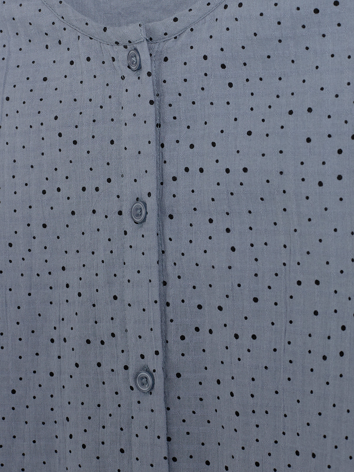 Blue fabric with black polka dots features three buttons down the center, creating a simple, patterned surface, likely part of a garment or blouse.