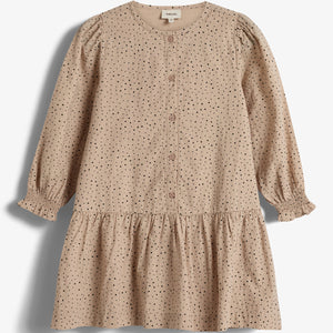 A beige, long-sleeved dress with black polka dots and front buttons rests on a plain white background. The dress features a gathered skirt and elasticized cuffs. Tag reads: "Prénatal".