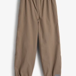 Eine beige Hose liegt flach auf einem weißen Hintergrund. Sie hat einen elastischen Bund und elastische Beinabschlüsse. Ein graues Etikett mit der Aufschrift "POLARN O.PYRET" befindet sich am Bein.