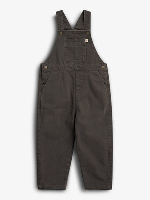 Dark brown children's overalls lie flat against a white background, featuring adjustable straps, a chest pocket, and side pockets secured with metal buttons.