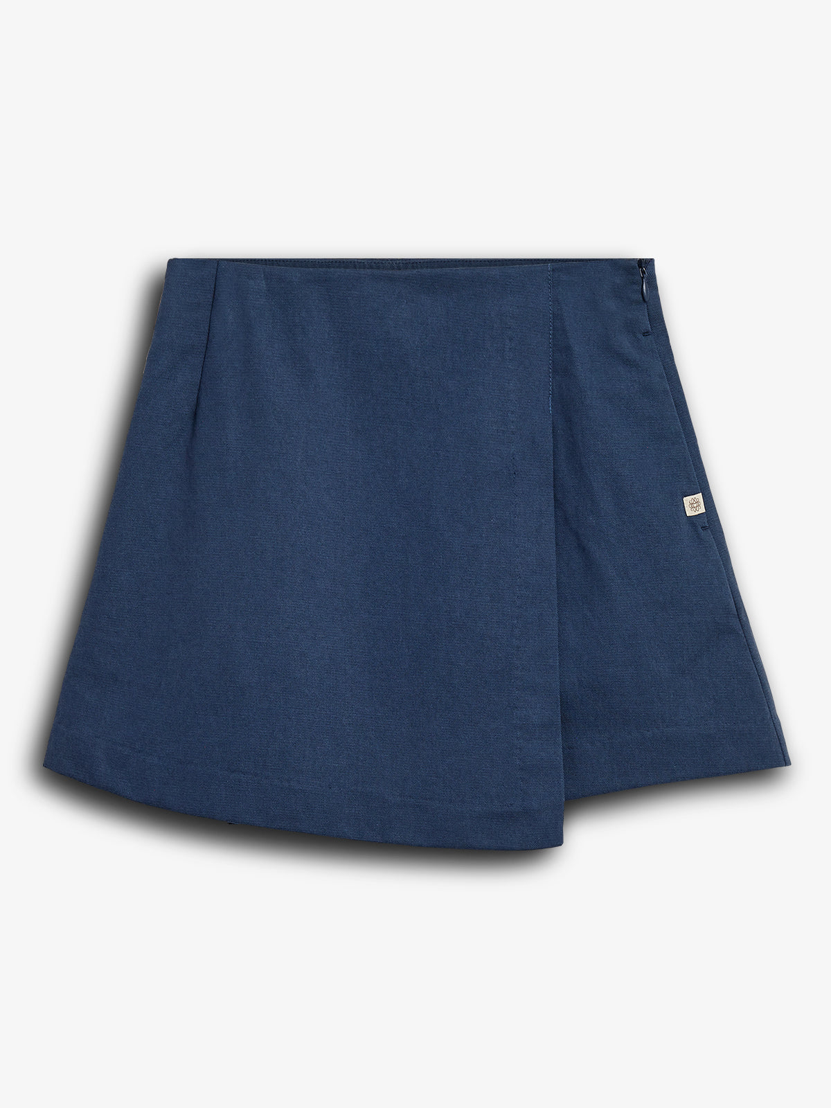 A navy blue skort with pleats and a side zipper is displayed against a plain white background, featuring a small rectangular label on the side.