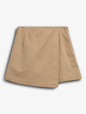 The object is a beige, A-line skirt with a wrap-over front design, lying flat. It features an elastic waistband and a small side tag. The background is plain white.