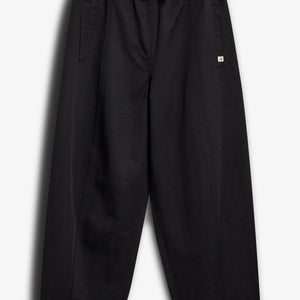 Loose black pants hang against a white background. They feature an elastic waistband with a drawstring, side pockets, and a small square logo on the front.