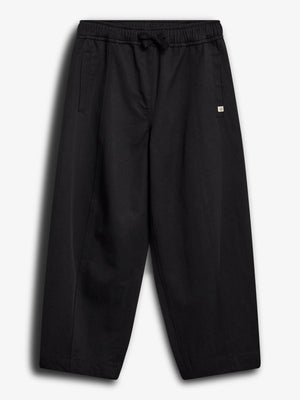 Loose black pants hang against a white background. They feature an elastic waistband with a drawstring, side pockets, and a small square logo on the front.