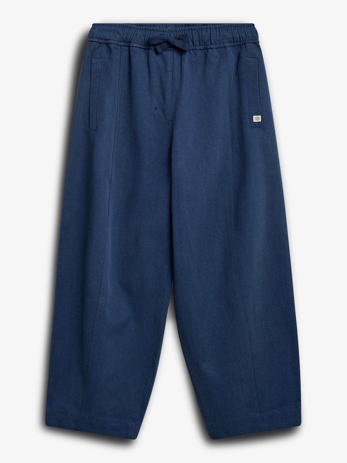 Blue pants with an elastic waistband and drawstring are laid flat on a white background. They feature side pockets and a small square logo on the right hip.