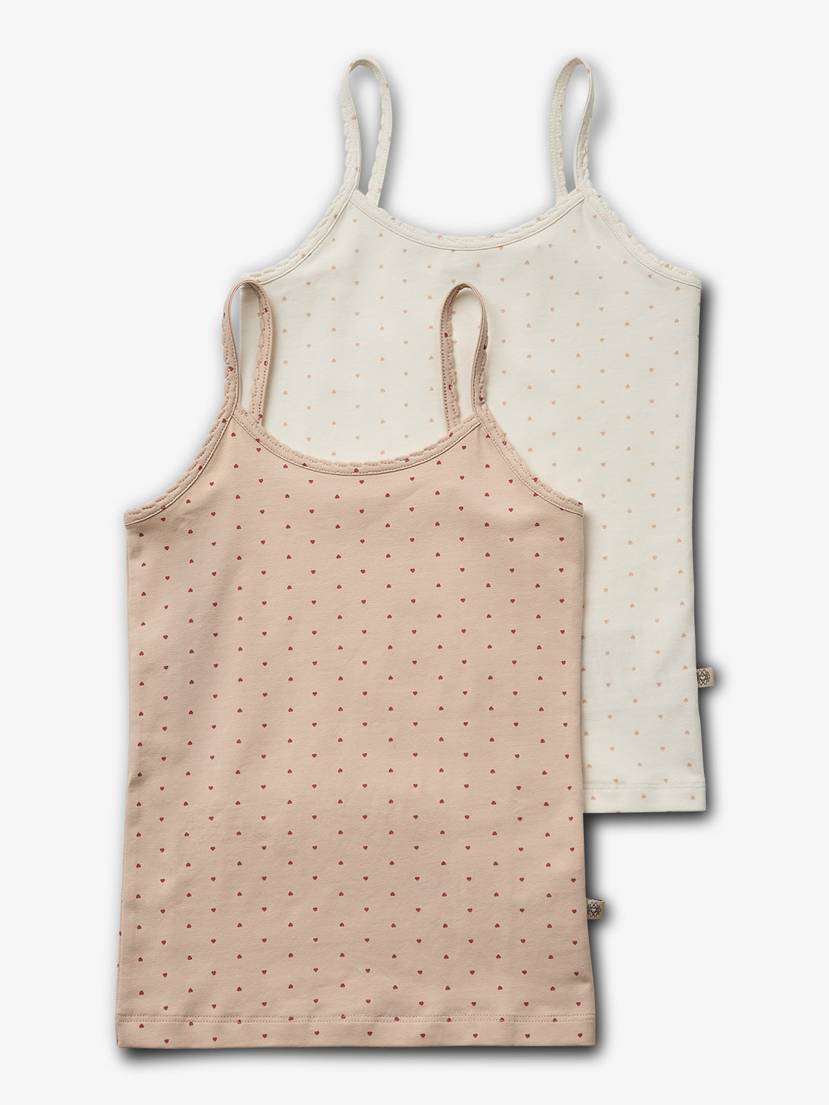 Two sleeveless tops with spaghetti straps are laid flat. One is beige, one white, both featuring small dotted heart patterns. They overlap slightly, set against a plain background.