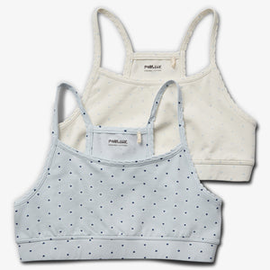 Two soft cotton bralettes are layered; one light blue with small heart patterns, the other off-white with similar patterns. Both display the text: "POMPdeLUX ORGANIC COTTON" on tags.