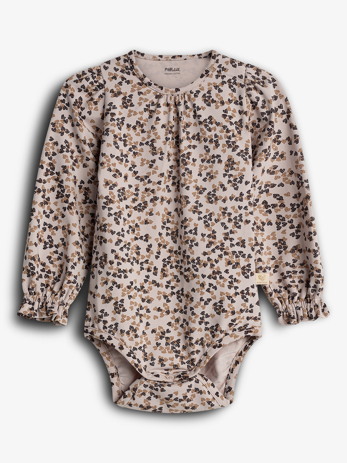 A long-sleeve baby onesie displays a floral pattern in brown and black on a light background. The garment has ruffled cuffs and is labeled “POMPdeLUX ORGANIC COTTON.”