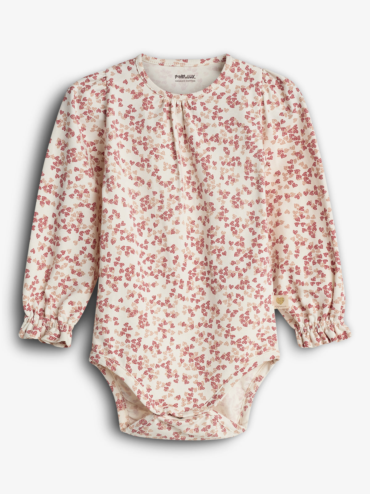A long-sleeved baby onesie with a red floral pattern on a cream background. "POPUPSHOP ORGANIC COTTON" is printed on the label inside the collar, set against a plain backdrop.