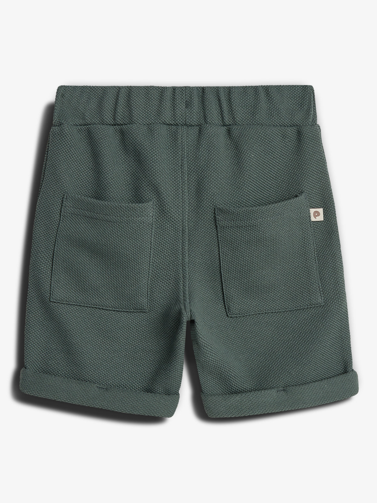 Green textured shorts have an elastic waistband and two rear pockets. The shorts are folded at the cuffs. The small label on the right pocket features a design resembling a stylized letter "P". The background is plain white.