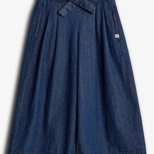 Dark blue denim culottes, featuring a tied waist belt, hang against a plain white background. The wide-legged design includes subtle pleats and a small sewn label on the upper right side.