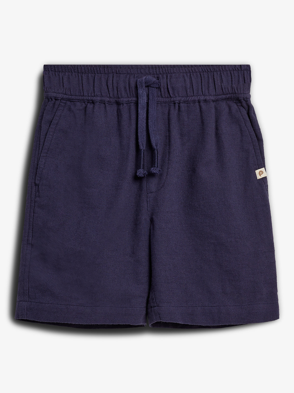 Navy blue shorts lie flat, featuring an elastic waistband with drawstrings and side pockets. A small beige tag is visible on the right side, set against a plain white background.