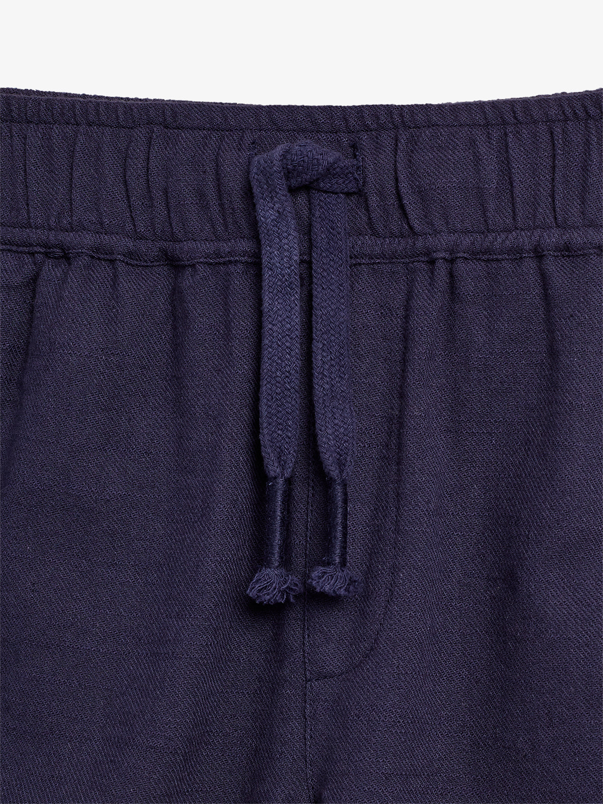 Dark blue drawstring is looped through an elastic waistband, creating a gathered effect in the fabric, suggesting comfortable, casual clothing in a close-up view.