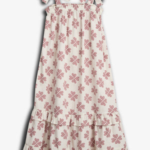 A white dress with red floral patterns hangs still, featuring adjustable shoulder tie straps and a tiered ruffled hem, set against a plain white background.