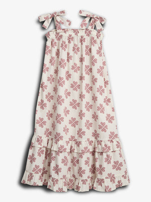 A white dress with red floral patterns hangs still, featuring adjustable shoulder tie straps and a tiered ruffled hem, set against a plain white background.