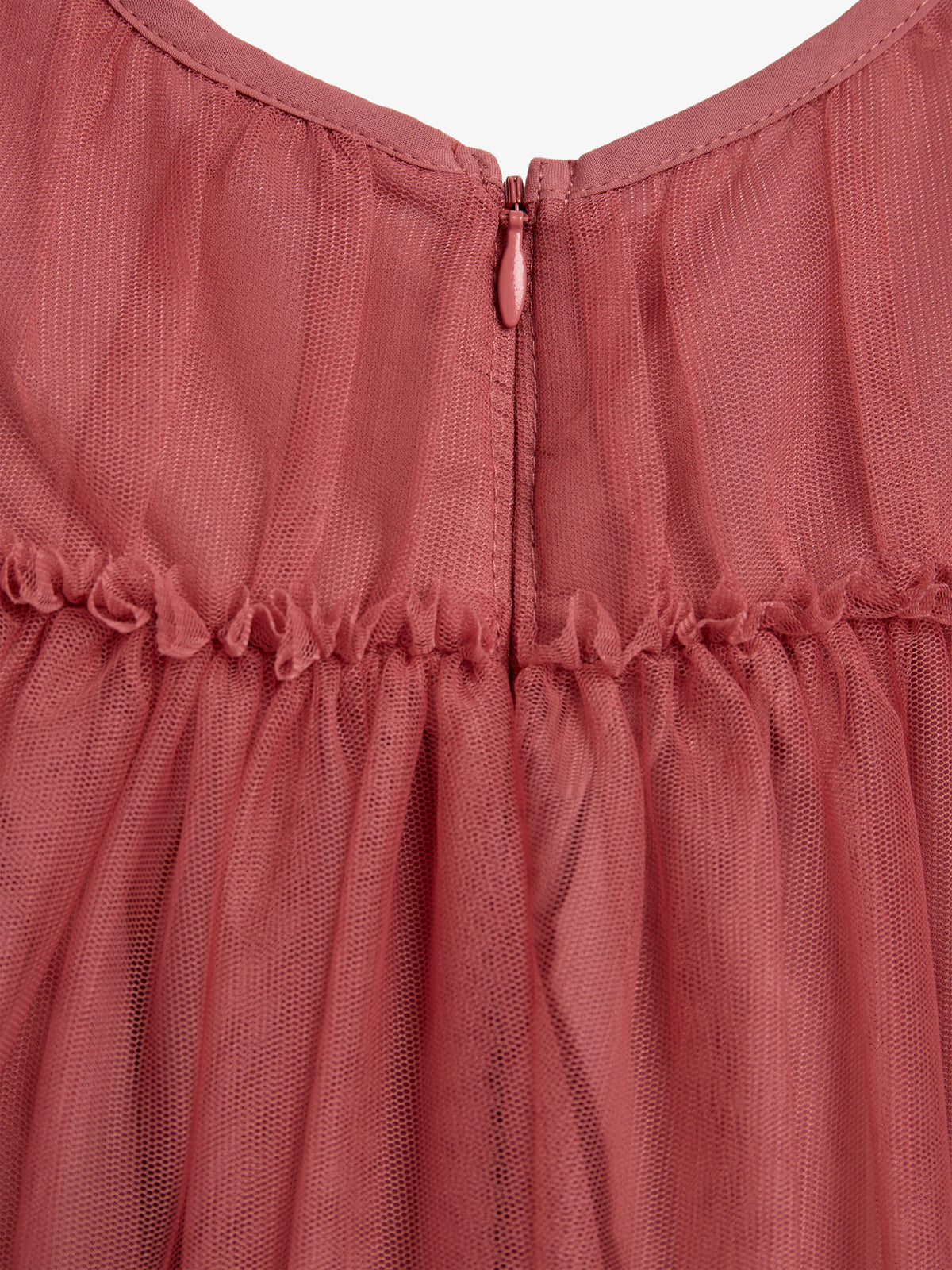 A pink sheer fabric dress features a closed zipper at the back, with gathered detailing at the waist, set in a plain studio background.
