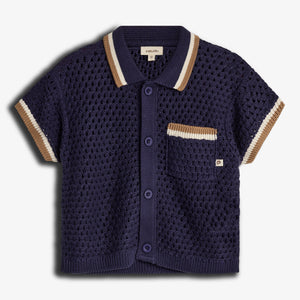 A navy blue, short-sleeved, knitted cardigan with button closure and striped collar and sleeves, features a pocket with beige and white accents. Label reads "pimaluLino." Background is plain white.