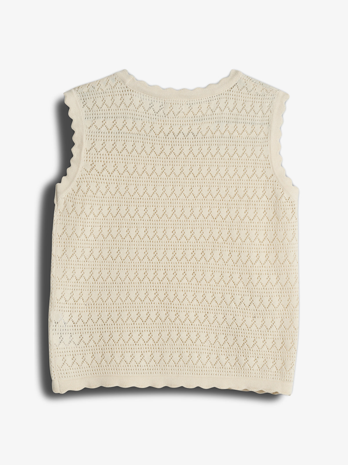 A sleeveless, cream-colored knitted top features a scalloped edge and intricate patterned design. It lies flat against a plain white background.