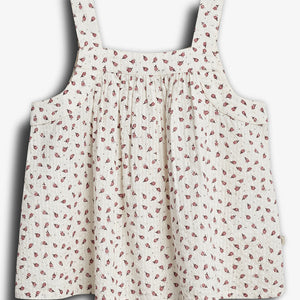 White sleeveless top with wide straps, featuring a pattern of small red flowers. The garment hangs freely, highlighting its loose, flowing design against a plain background.