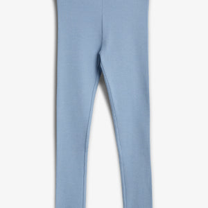 Eine hellblaue Leggings hängt ruhig. Sie ist aus einem gerippten Stoff gemacht, mit einem elastischen Bund und gekräuselten Abschlüssen, auf einem neutralen Hintergrund.