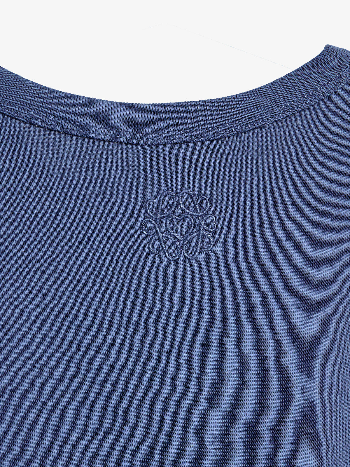 A close-up of a blue fabric's neckline features a stitched pattern of intertwined shapes. It creates an elegant, textured design, suggesting an article of clothing in a well-lit environment.