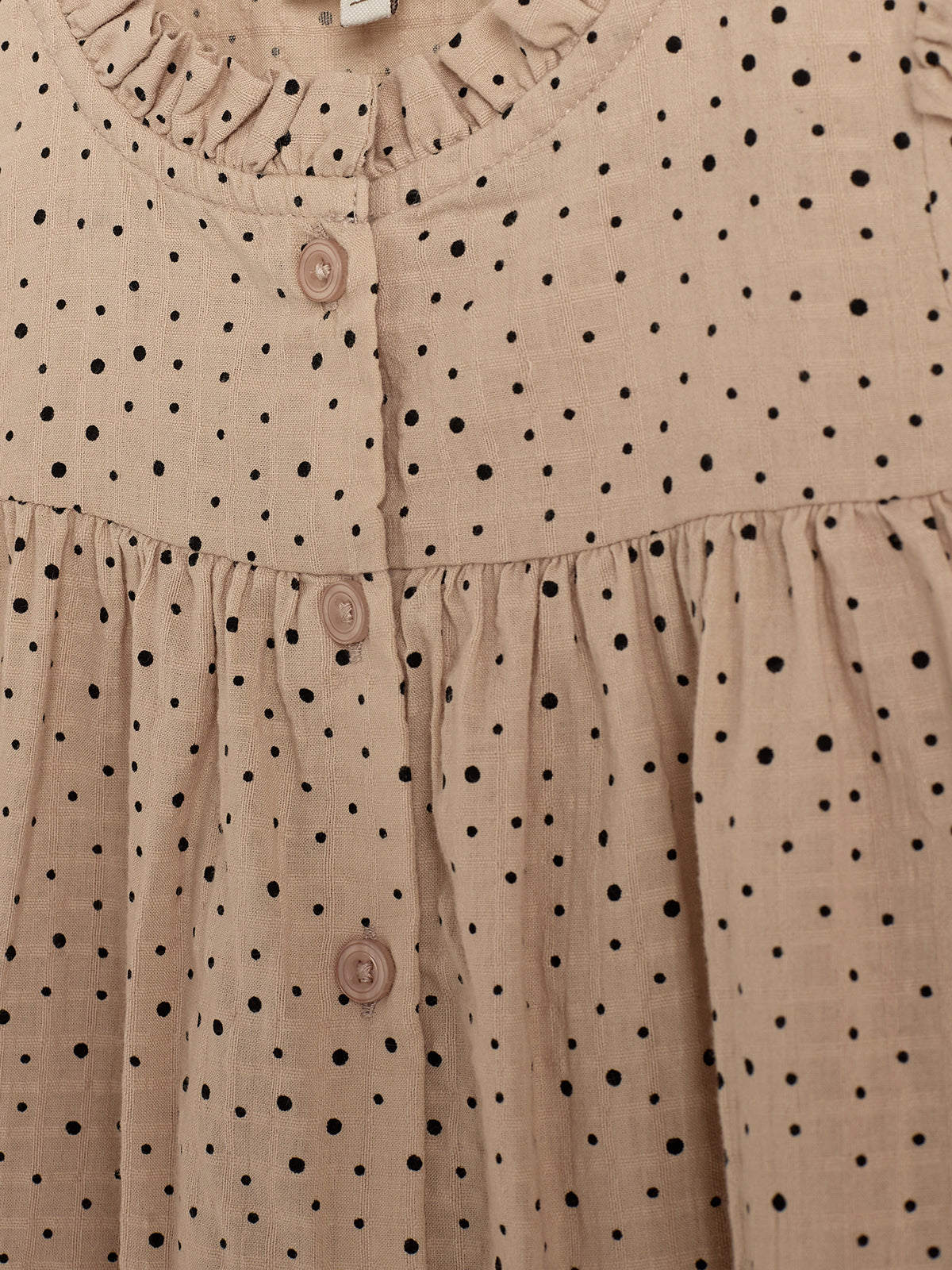Pink polka-dot dress with black spots, featuring a ruffled collar and three buttons down the front, set against a plain background.