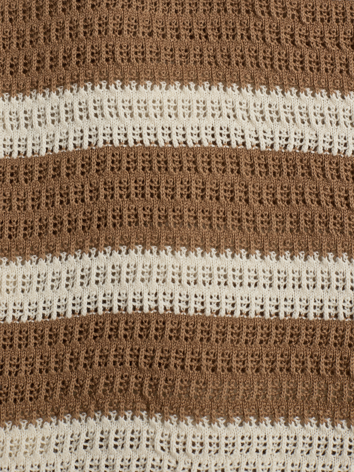 Brown and cream crochet fabric appears with alternating textured stripes, creating a patterned surface. The background is plain, highlighting the intricate, repeating lace-like design of the material.