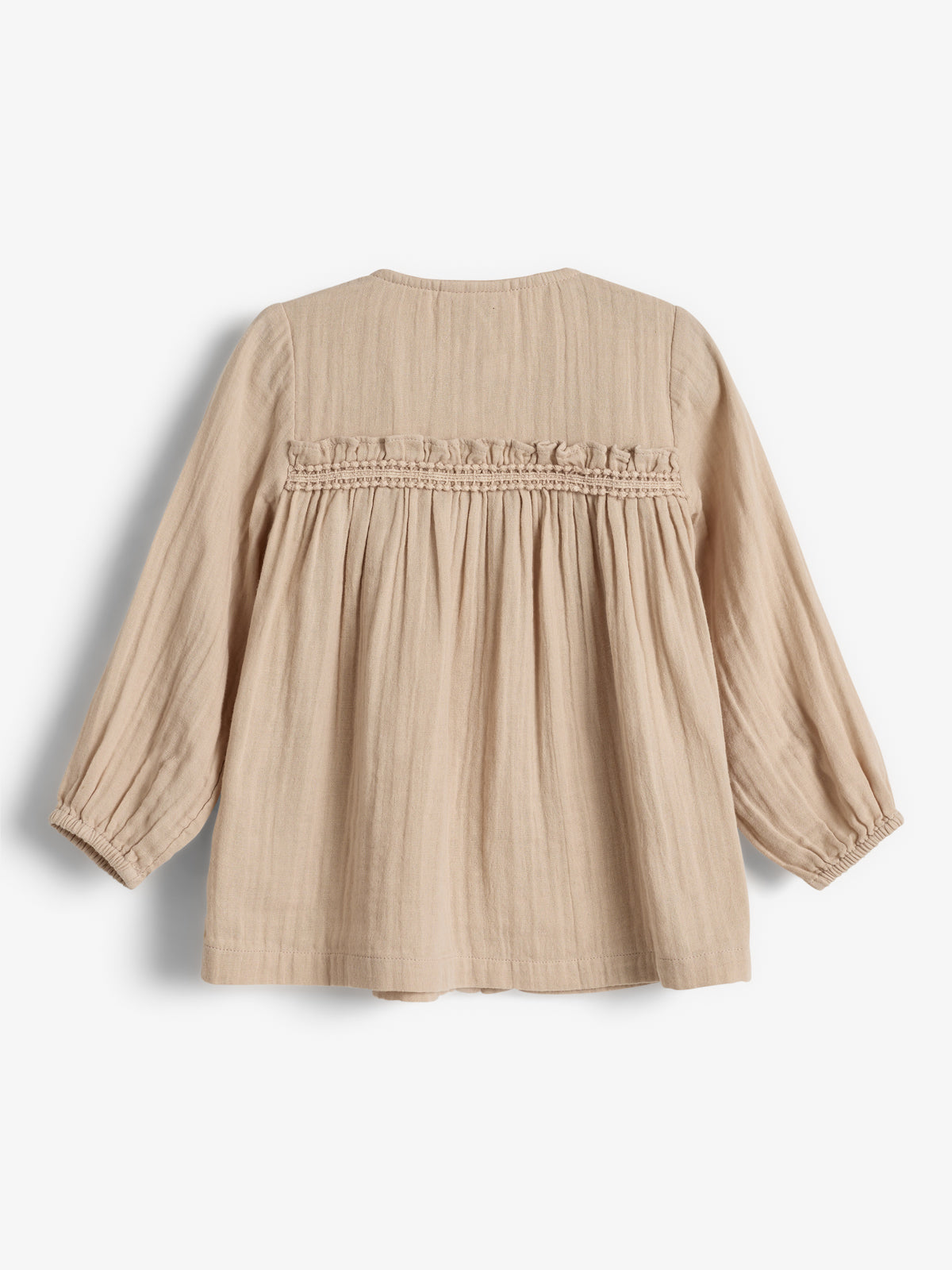 Beige Bluse mit langen Ärmeln, losem Schnitt und gerüschten Details am Rücken, liegt auf weißem Hintergrund.