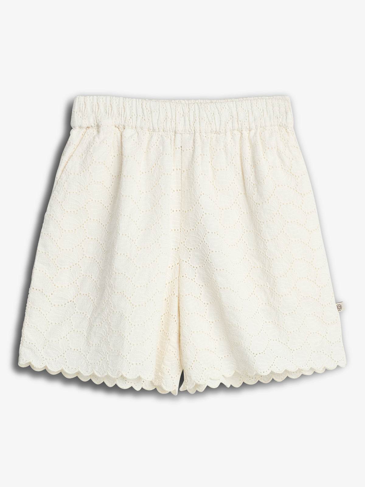 White lace shorts with scalloped edges sit against a plain background. The fabric features an intricate, circular eyelet pattern, with an elastic waistband for comfort.