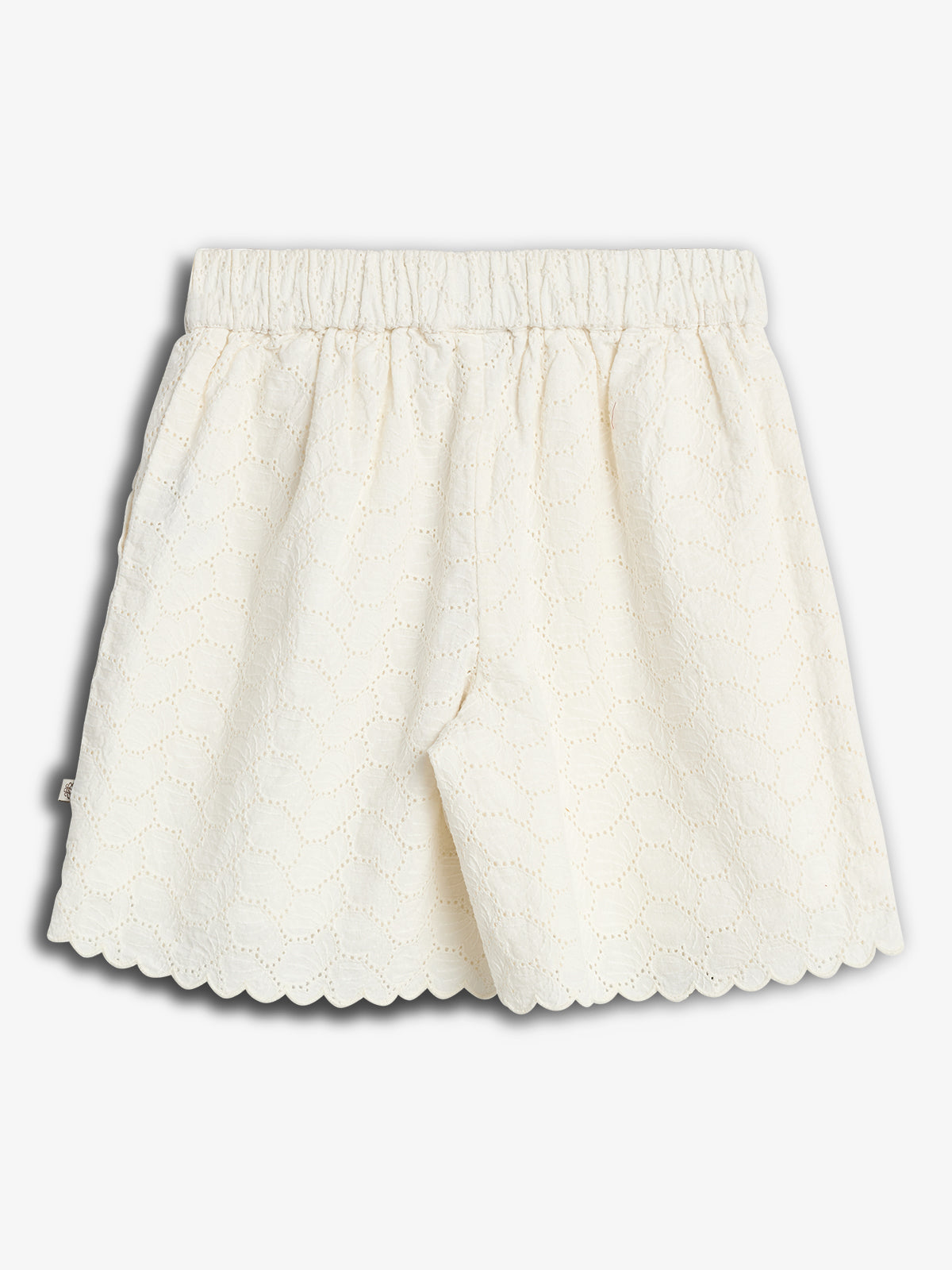 White lace shorts with an elastic waistband, featuring a scalloped hem and intricate eyelet pattern, set against a plain light gray background.