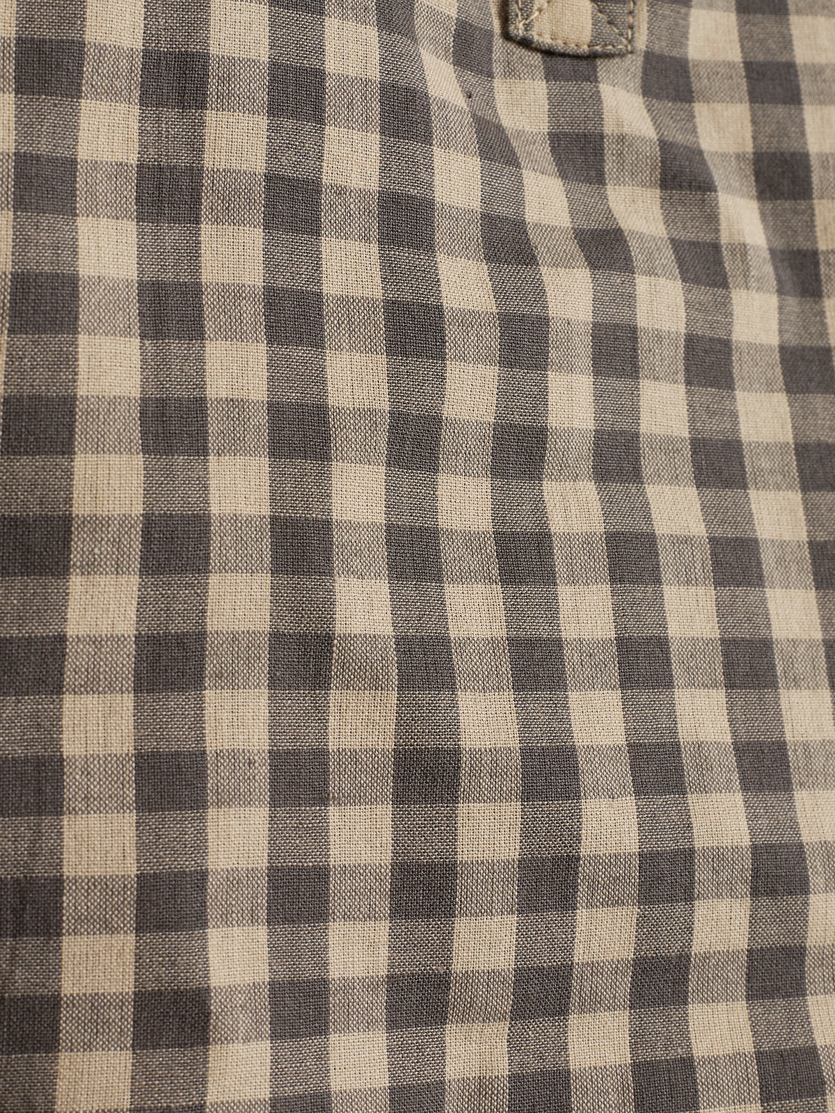 Ein Stoff präsentiert ein schwarz-beiges Karomuster. Die quadratischen Muster sind gleichmäßig verteilt, erzeugen ein klassisches Design, und sind in einer Umgebung ohne weitere Objekte platziert.