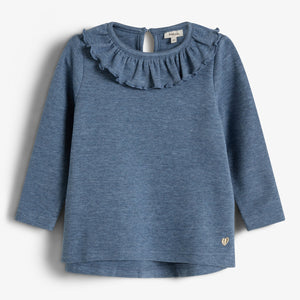 Ein blaues Sweatshirt für Kinder mit Rüschenausschnitt und langen Ärmeln, präsentiert auf einem neutralen Hintergrund. Ein kleiner, goldener Herz-Logo befindet sich unten rechts.