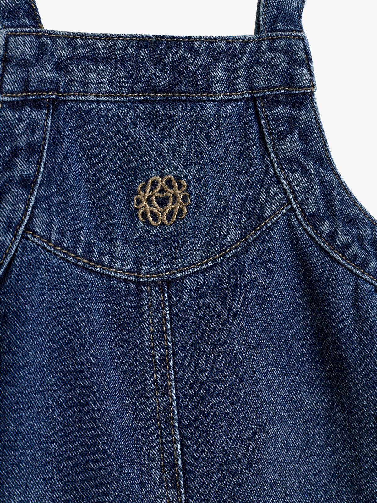 Jeansstoff-Latz mit gesticktem Herzmuster sitzt mittig auf blauem Hintergrund. Stoffnähte sind sichtbar, verleihen Struktur und Details.