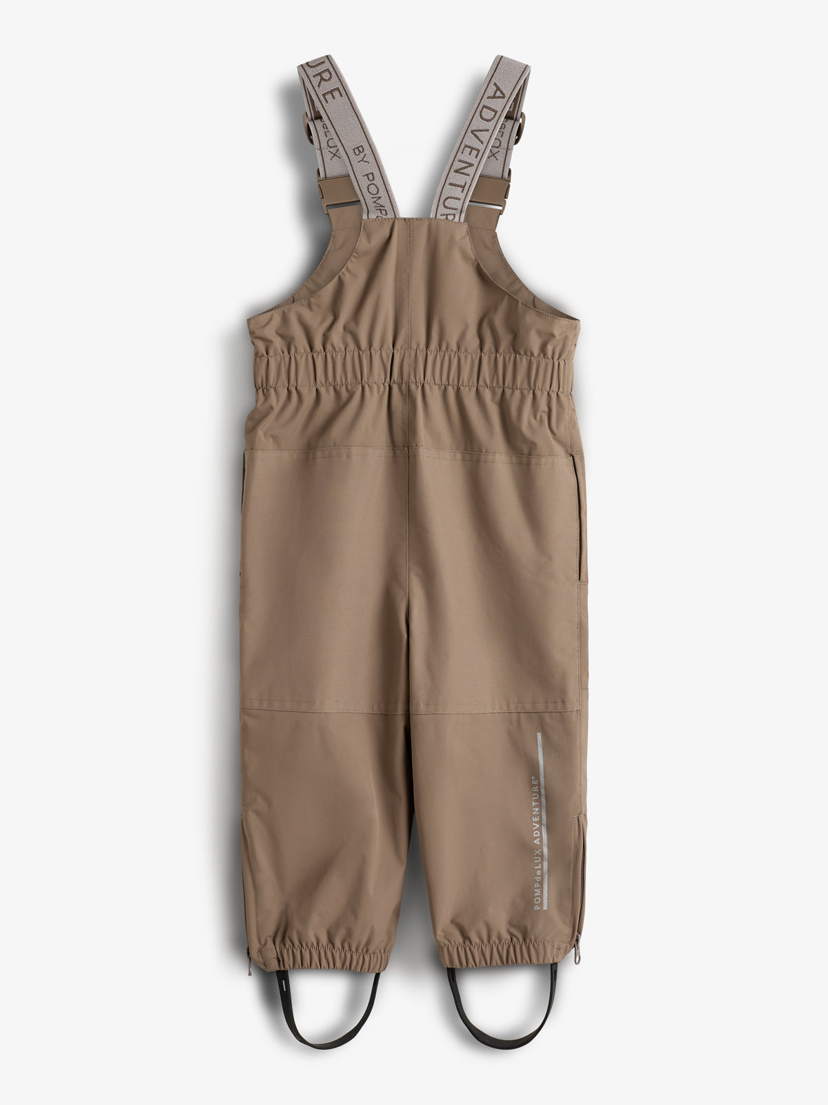 Latzhose in Beige, mit verstellbaren Trägern, die "ADVENTURE" und "BY POMME" zeigen, elastischem Bund und Beinabschlüssen. Im Hintergrund ein neutraler, weißer Untergrund.