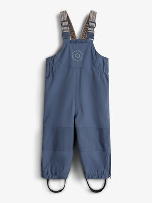 Eine blaue Kinderregenhose mit verstellbaren Trägern ist auf einem neutralen Hintergrund dargestellt. Auf der Brust steht: "ROMPDE LUX ADVENTURE".