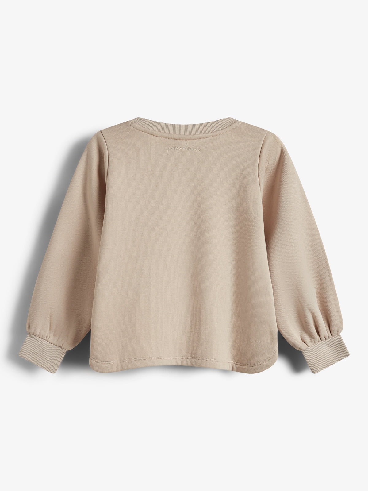 Ein beige Langarmshirt hängt ruhig in einem neutralen Hintergrund. Es hat eng anliegende Bündchen und den gestickten Text „Joules“ am oberen Rücken.