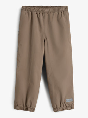 Beige Kinderhose liegt flach mit elastischen Bündchen am oberen und unteren Rand. Im rechten unteren Bereich befindet sich ein kleines Etikett mit der Aufschrift: "FORMKIDS". Hintergrund ist neutral.