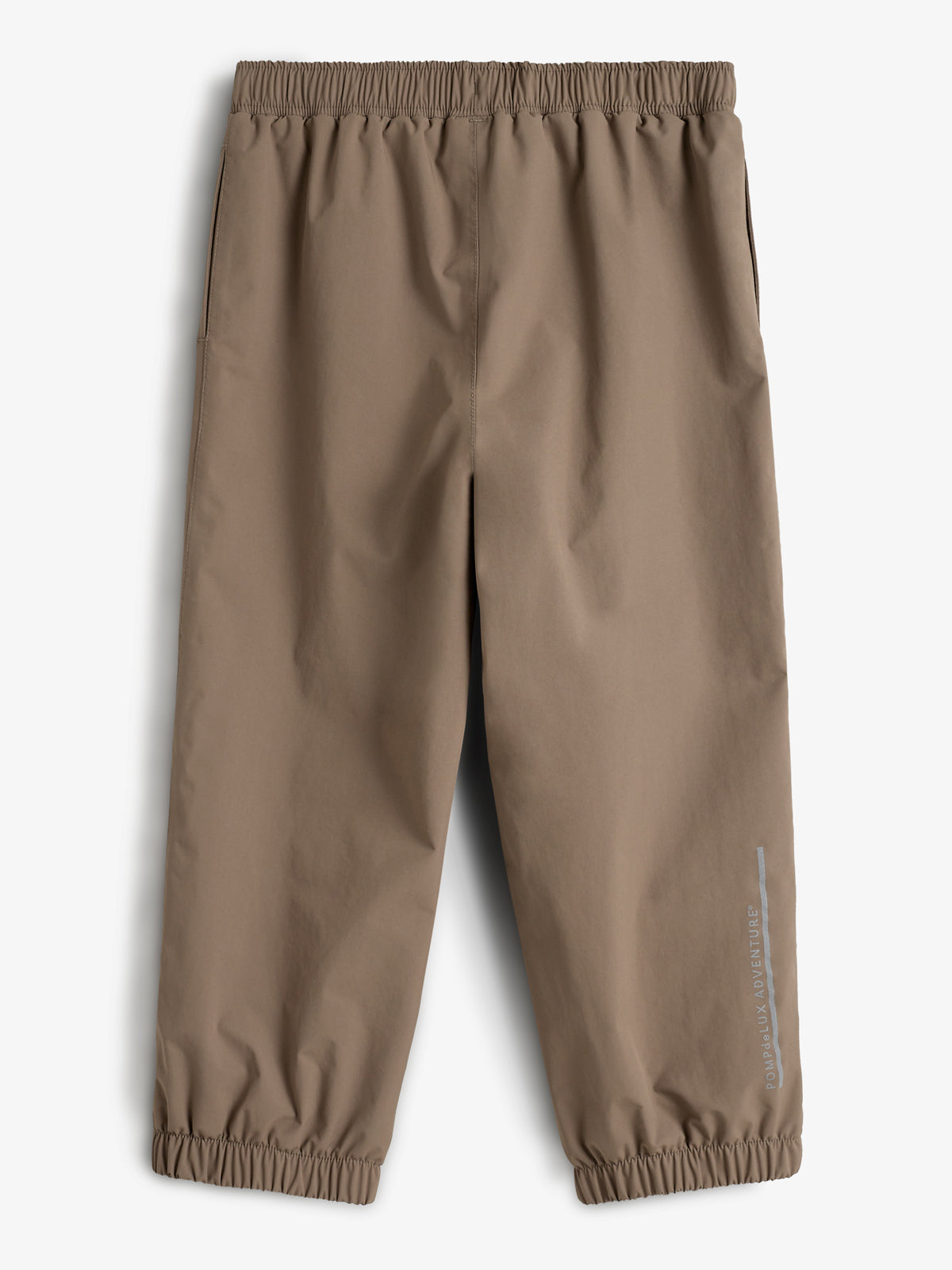 Die braune Hose hat einen elastischen Bund und Beinabschlüsse. Sie ist glatt und schlicht, mit dem Text "Polarn o. Pyret ADVENTURE" an der Seite. Der Hintergrund ist weiß.